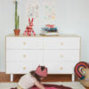 Child playing on Oeuf Rainbow Rug in front of Oeuf Fawn Dresser