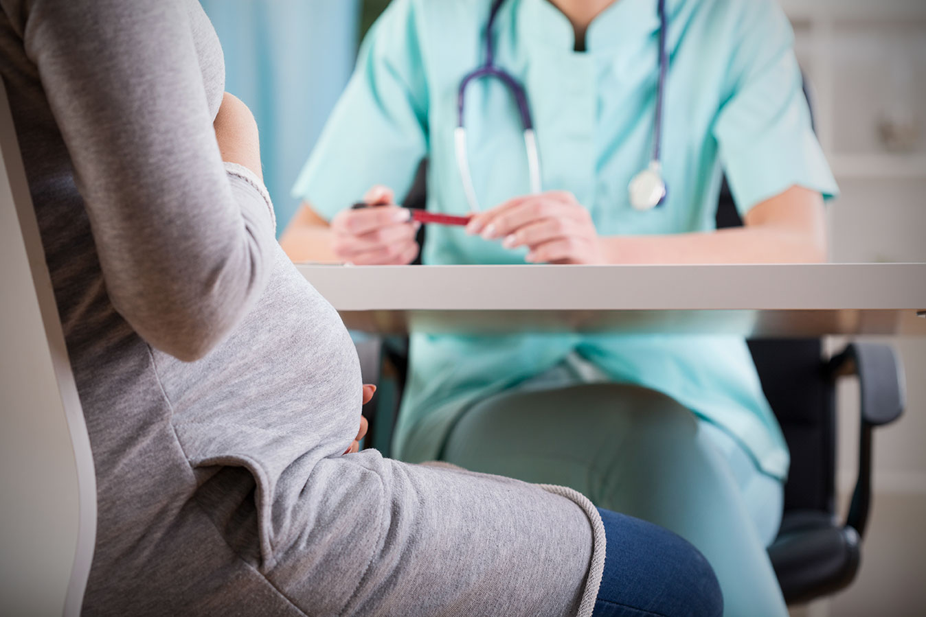 Pregnant Woman Sits with Doctor