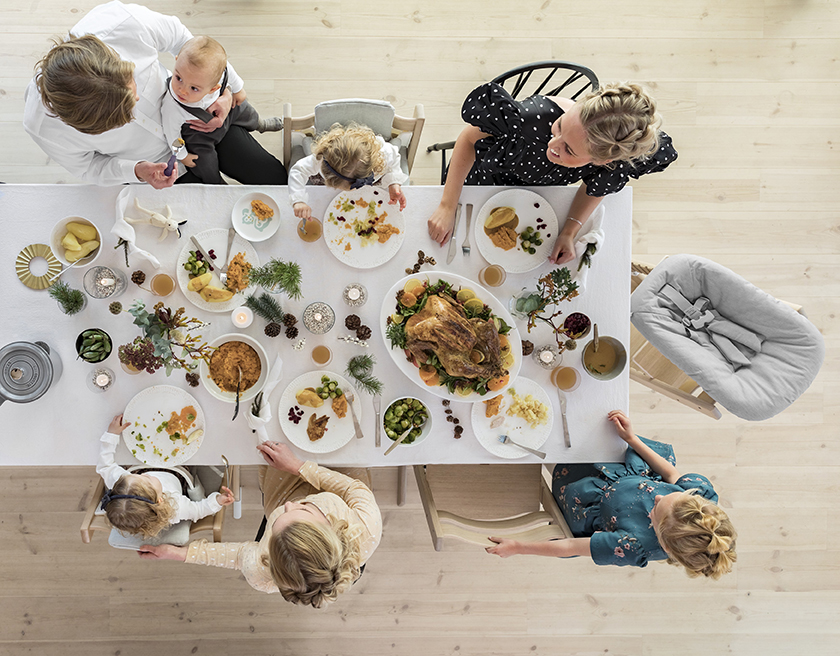 Dining table meal time with multiple kids and babies eating in different positioned Tripp Trapps around the table with their family. 